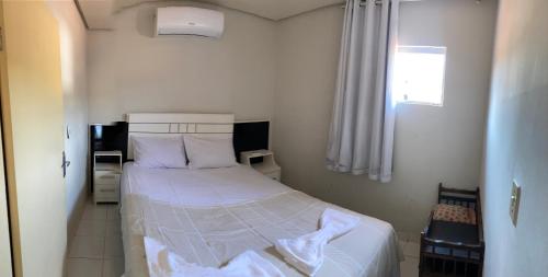 a small bedroom with a bed with white sheets at Casa my House in Lençóis