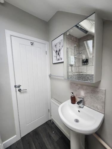 a white bathroom with a sink and a mirror at Modern Spacious Apartment Steps from City Centre in Norwich