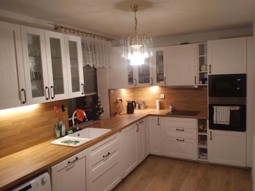 a kitchen with white cabinets and a chandelier at Cottage House in Stožec
