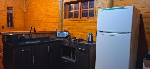 a kitchen with a white refrigerator and a sink at Cabana Vermelha in São Francisco de Paula