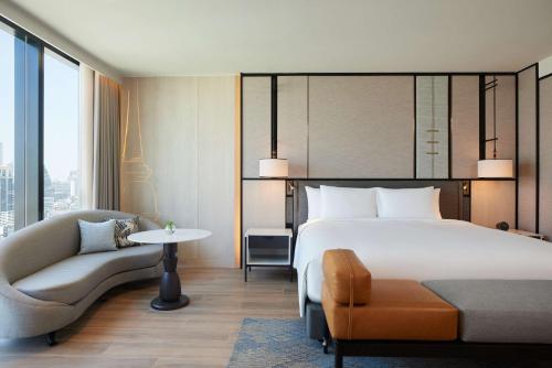 a hotel room with a bed and a chair at dusitD2 Samyan Bangkok in Bangkok