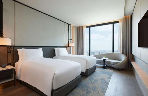 a hotel room with two beds and a couch at dusitD2 Samyan Bangkok in Bangkok