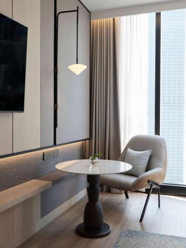 a living room with a table and a chair and a tv at dusitD2 Samyan Bangkok in Bangkok