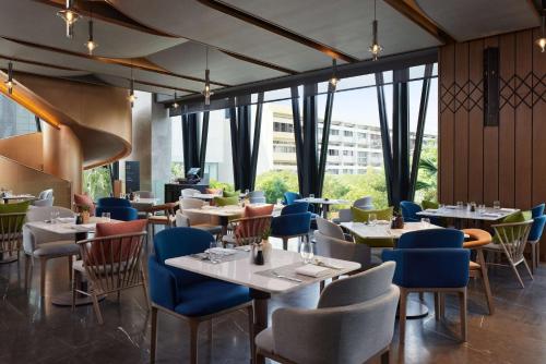 a restaurant with tables and chairs and windows at dusitD2 Samyan Bangkok in Bangkok