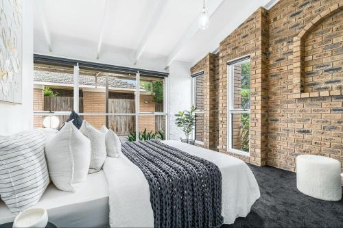 Un dormitorio con una cama y una pared de ladrillo. en Quiet & Cozy 4 Bedroom Home, en Norlane