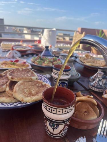a table with plates of food and a cup of coffee at taghoba surf house in Tamraght Ouzdar