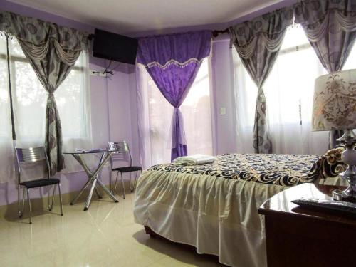 a bedroom with a bed with purple curtains and a table at El Grano De Oro Hotel in Tupiza