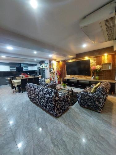 a living room with couches and a flat screen tv at Casa de Campo Santo Tomas in Iquitos