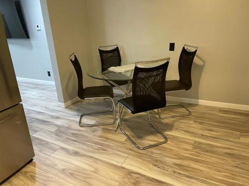 a glass table and four black chairs in a room at Cozy Roomy family sized apartment on major bus route close to all in Orchard Park