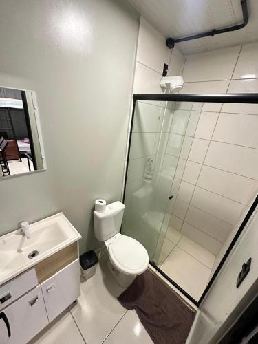 a bathroom with a shower and a toilet and a sink at Pousada e Lofts Jardim C in Jaú