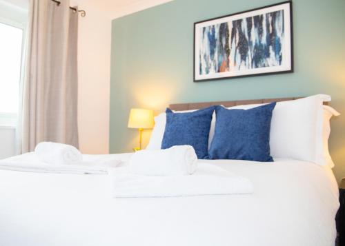a bedroom with a large white bed with blue pillows at Parkside House Stevenage in Stevenage