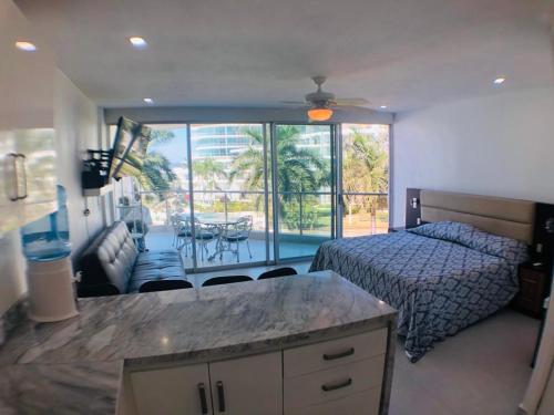 a bedroom with a bed and a kitchen with a table at Aria Ocean Beachfront Condos in Nuevo Vallarta