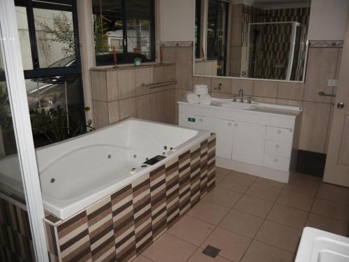 a bathroom with a large tub and a sink at Quand0ng Valley Inn The Waterfall Room in Minynon
