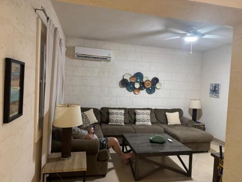 a person sitting on a couch in a living room at Golden Acre Beach Villa-2 mins walk - Alleynes Bay in Saint James