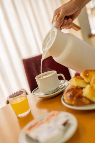 圣贝尔纳多Hotel Carmen的把咖啡倒进桌上的杯子里的人