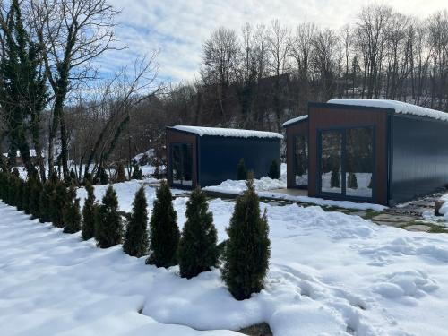 a blue building in the snow with a line of trees at HARIZMA LUX Banja Vrujci in Popadić