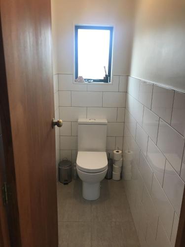 a small bathroom with a toilet with a window at Nikau Nook in Raglan