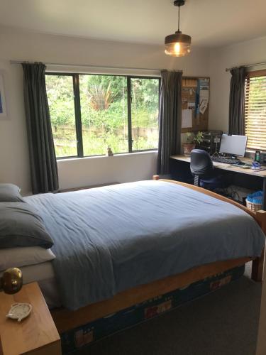 a bedroom with a bed and a desk with a computer at Nikau Nook in Raglan