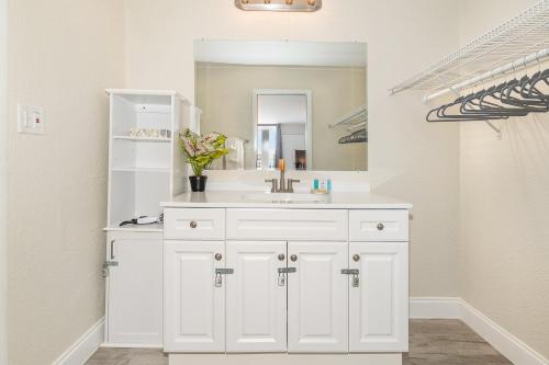 a white bathroom with a sink and a mirror at Charming Suite: Smart TV, Modern Amenities & Pool Access in Kissimmee
