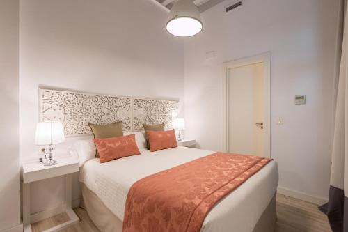 a white bedroom with a bed and a table and lamp at Palacio Cabrera - Lillo in Granada