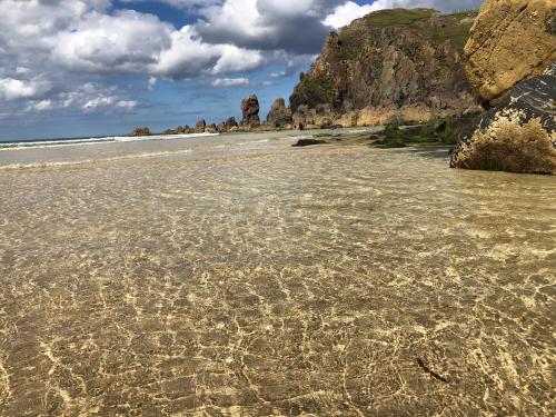 a sandy beach with rocks in the water at Taigh Tuaram in Carloway