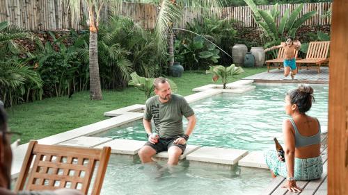a man and a woman sitting in a swimming pool at Villa Elior Selong Belanak, South Lombok in Selong Belanak