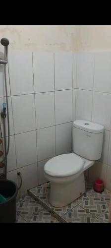 a bathroom with a toilet in a white tiled wall at PONDOK SITI RAWIYAH Guest House in Bukittinggi