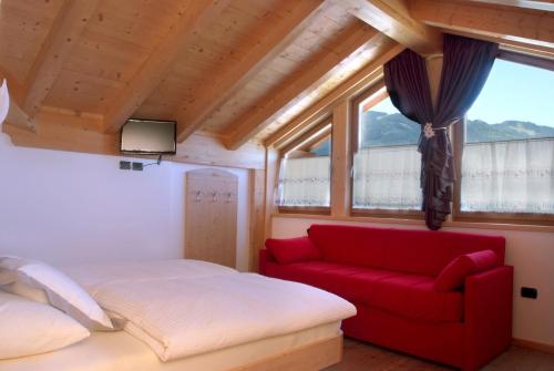 a bedroom with a red couch and a window at Agritur Maso Chemela in Cavalese