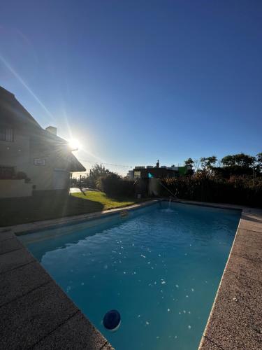 a blue swimming pool with the sun in the background at Chalet El Teson in Punta del Este