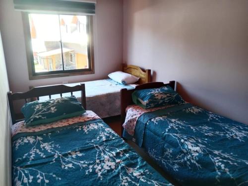 Un dormitorio con dos camas y una ventana. en Cabaña familiar Doris, en Coñaripe
