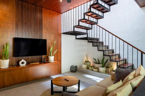 a living room with a spiral staircase in a house at Raya Villa by Betterplace in Canggu