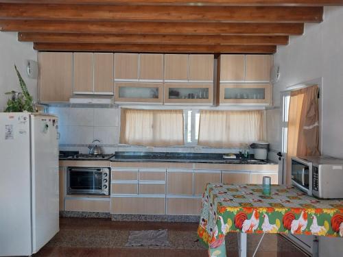 a kitchen with wooden cabinets and a table and a refrigerator at Big House in Merlo