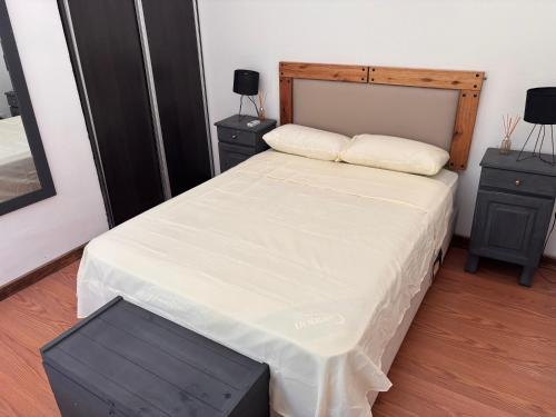 a bedroom with a bed with a wooden headboard at La Estancia in Ybarlucea