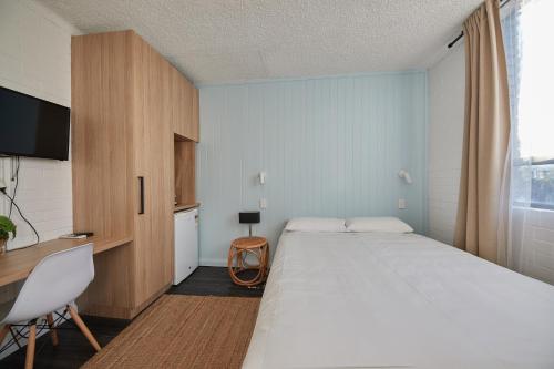 a bedroom with a large white bed and a desk at Little Coogee Hotel in Sydney