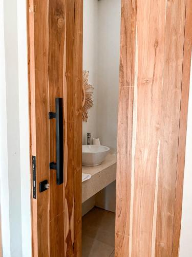 a wooden door leading to a bathroom with a sink at Villa Elior Selong Belanak, South Lombok in Selong Belanak