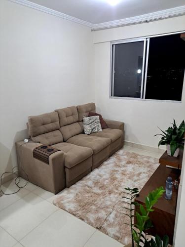 a living room with a brown couch and a window at Apto Completo, proximo ao Shopping in Taubaté