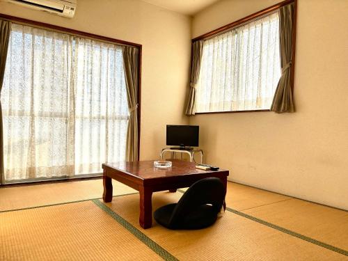 a room with a wooden table and a chair and a desk at ビジネスホテル美咲 in Sakaide