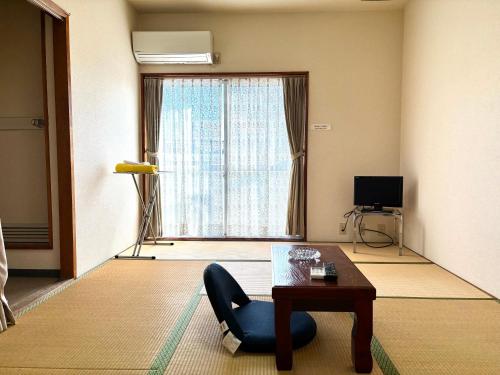 a living room with a chair and a table and a window at ビジネスホテル美咲 in Sakaide