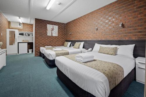a bedroom with two beds and a brick wall at Healesville Motor Inn in Healesville