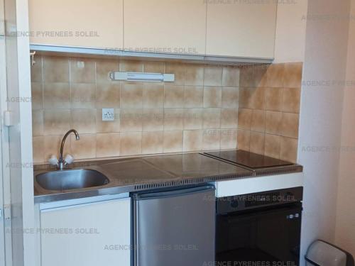 une petite cuisine avec un évier et une cuisinière dans l'établissement Appartement lumineux avec balcon près du lac - FR-1-295-204, aux Angles