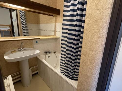 une salle de bain avec un lavabo et un rideau de douche dans l'établissement Studio-cabine avec balcon proche pistes et parking - FR-1-787-113, à Laveissière