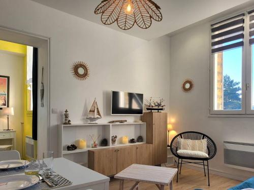un salon avec une télévision et une table dans l'établissement Studio cosy avec parking, à 100m du centre, proche plage - FR-1-788-47, à Merville-Franceville-Plage