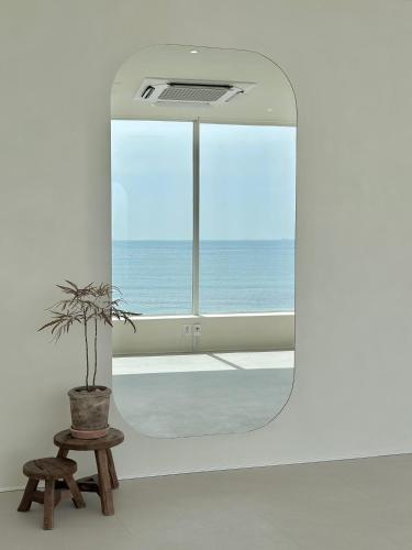 a mirror in a room with a potted plant at HoHo House Songjeong in Busan