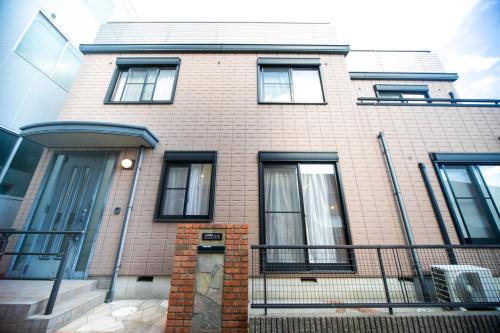 a brick house with black windows and a fence at Miraie Yokkaichi Takasagocho in Yokkaichi
