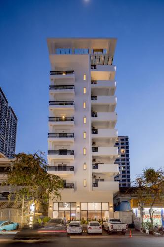 a tall white building with cars parked in a parking lot at WH Hotel 310 in Phnom Penh