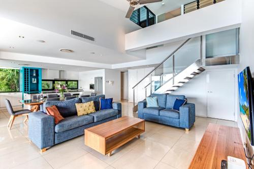 a living room with two blue couches and a table at Edge Apartments on Hamilton Island by HIHA in Hamilton Island