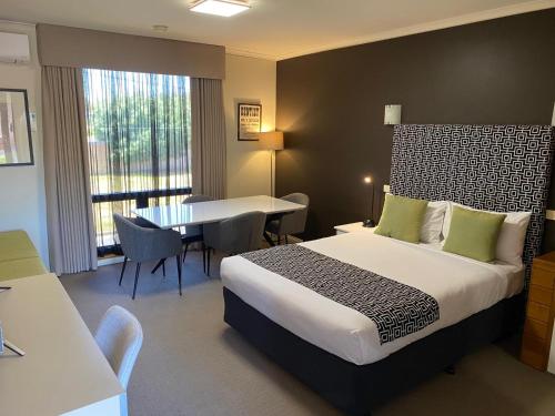 a hotel room with a bed and a dining room at Sovereign Park Motor Inn in Ballarat