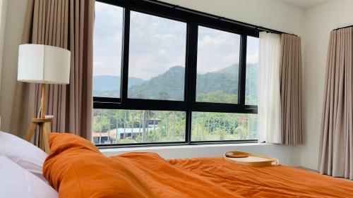 a bed with an orange blanket in front of a large window at ATATvilla Khaoyai with mountain rooftop view for party and BBQ in Mu Si