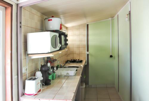 a small kitchen with a sink and a microwave at Maison charmante à Saint-Gilles les Bains in Saint-Gilles-les-Bains