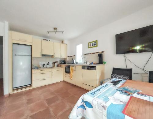 une grande cuisine avec une table et une télévision dans l'établissement Maison de vacances confortable avec jardin et terrasse au Lavandou, au Lavandou